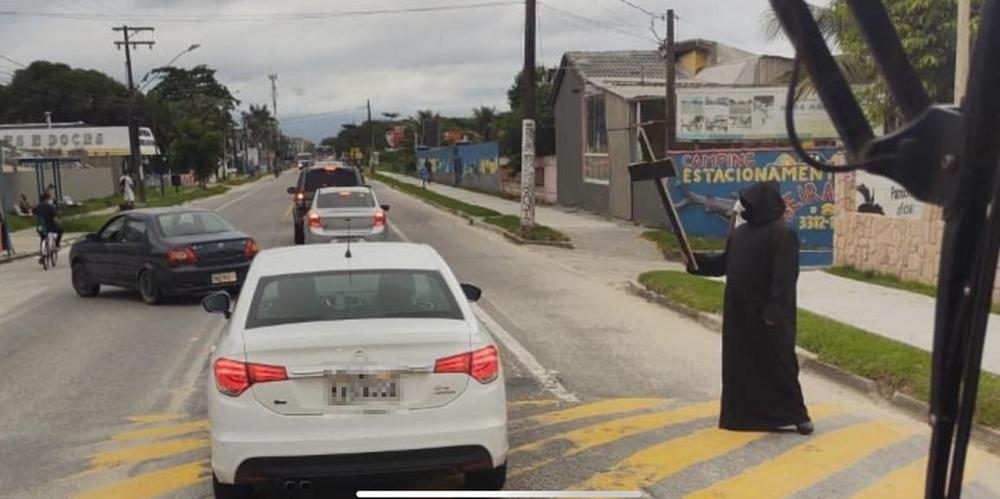 Homem vestido de morte recepciona turistas que insistiram em viajar para cidade do litoral de São Paulo